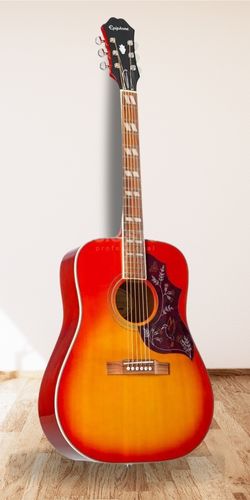 Epiphone Hummingbird Pro Acoustic Guitar on Wood Floor With White Wall Background