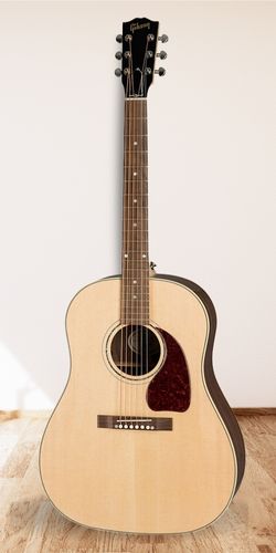 Gibson J-15 Acoustic Guitar on wood studio floor with a white wall as the background