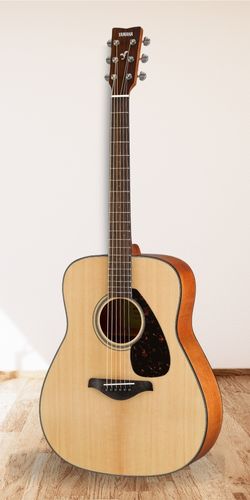Yamaha FG800 Acoustic Guitar on a white wall with wood floor underneath