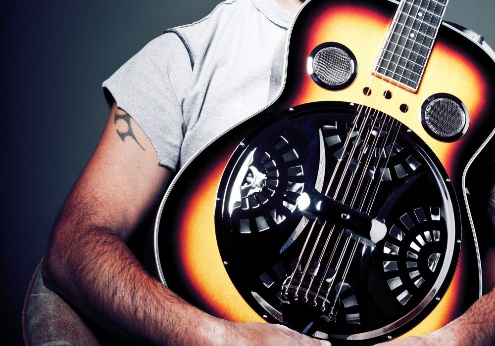 a guitarist holding a resonator guitar