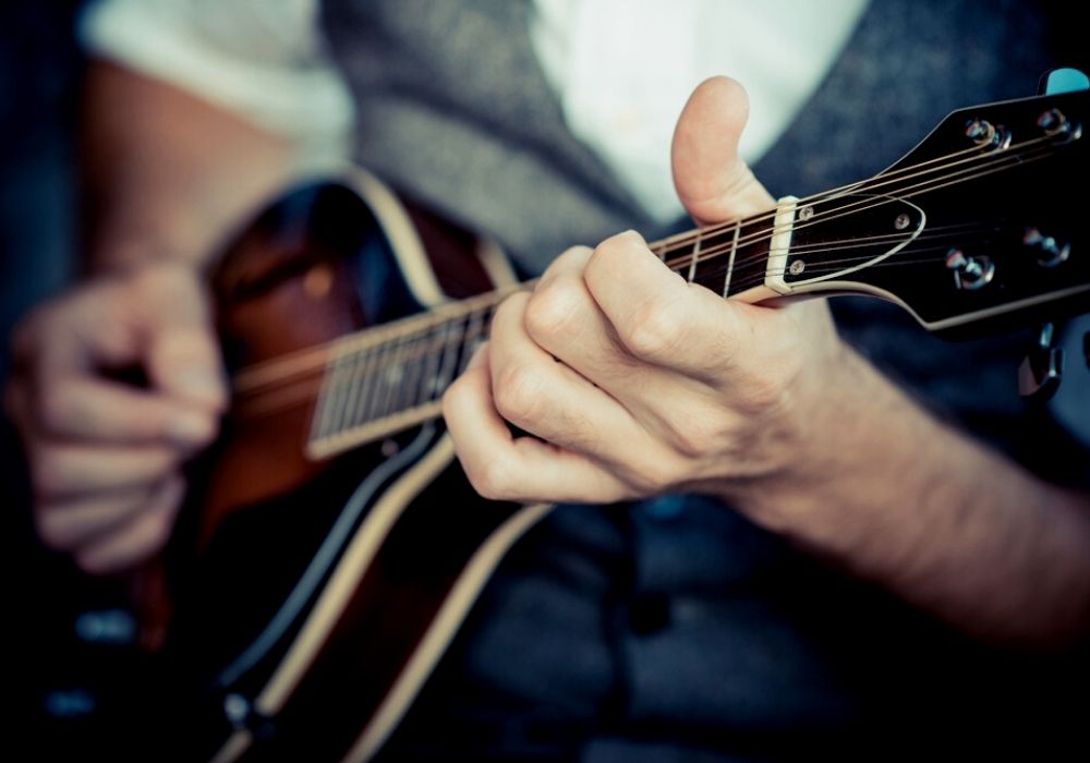 A close up hands hipster man playing mandolin instrument