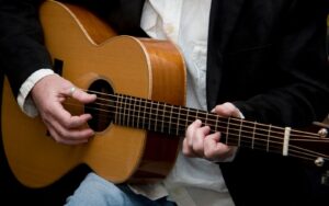 A musician strumming an acoustic guitar