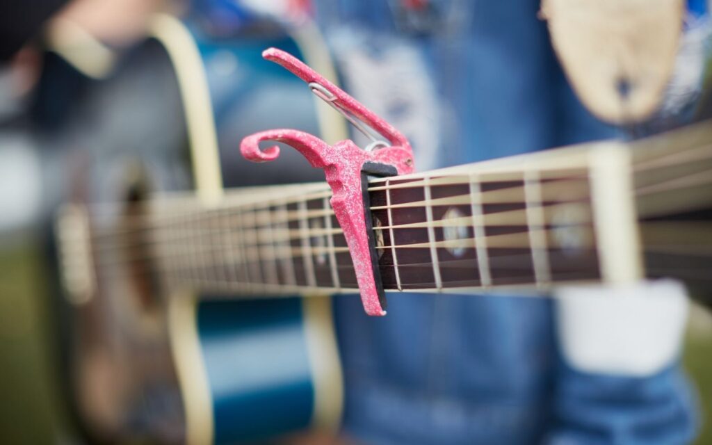 An acoustic guitar and a capo