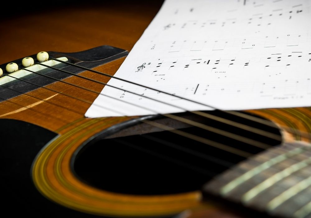 a close up of an acoustic guitar and a musical sheet for easy songs