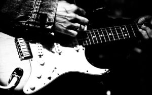 A close up of a electric guitar player on stage in black and white