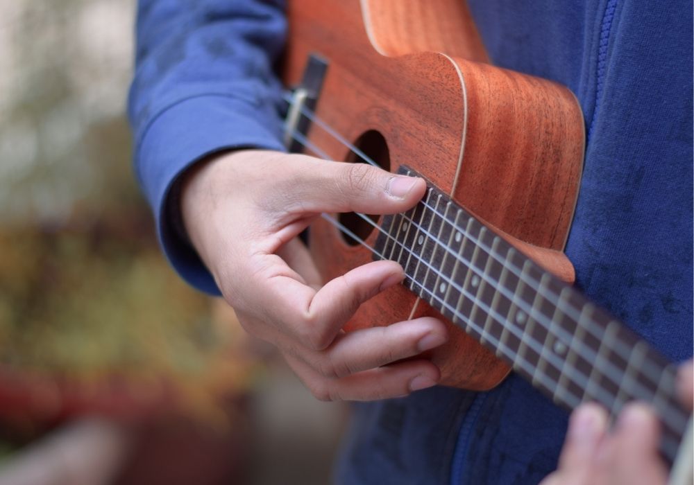 a musician plucking an intermediate ukulele