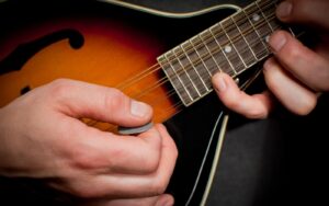 close up of a man's hands , picking , playing the mandolin