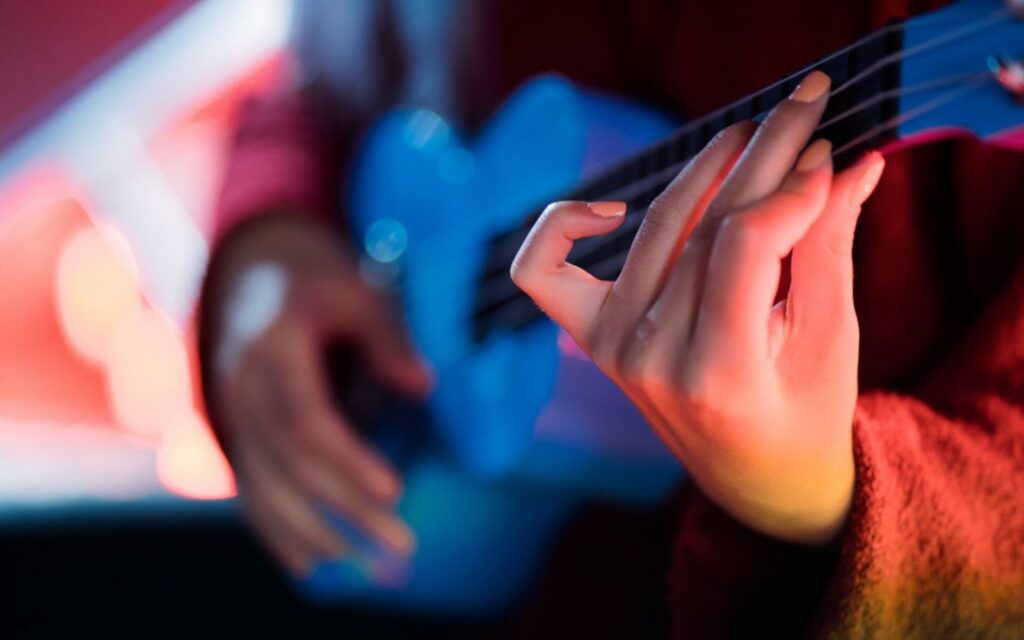 hands of young pretty girl playing on blue ukulele