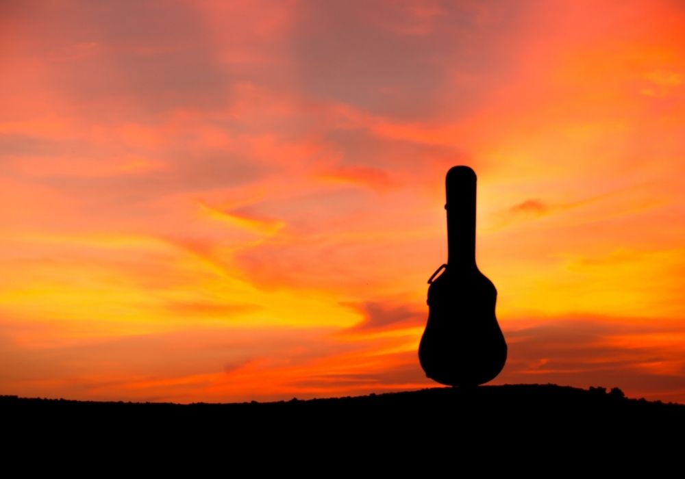 silhouette of a guitar case for flying at sunset