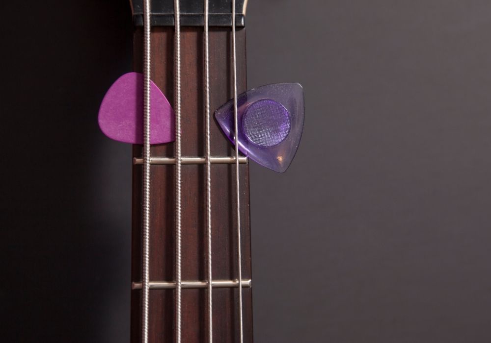 two bass guitar picks in amongst a bass neck with strings