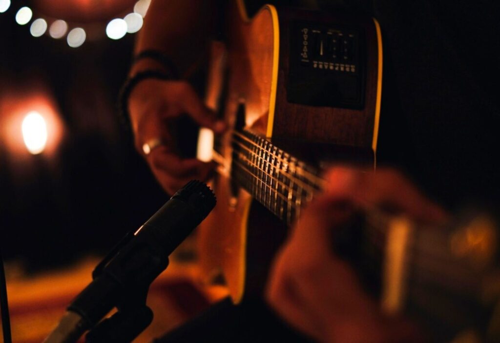 A man playing acoustic guitar in recording session with microphone