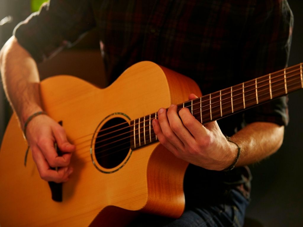 a musician strumming an acoustic guitar for jazz